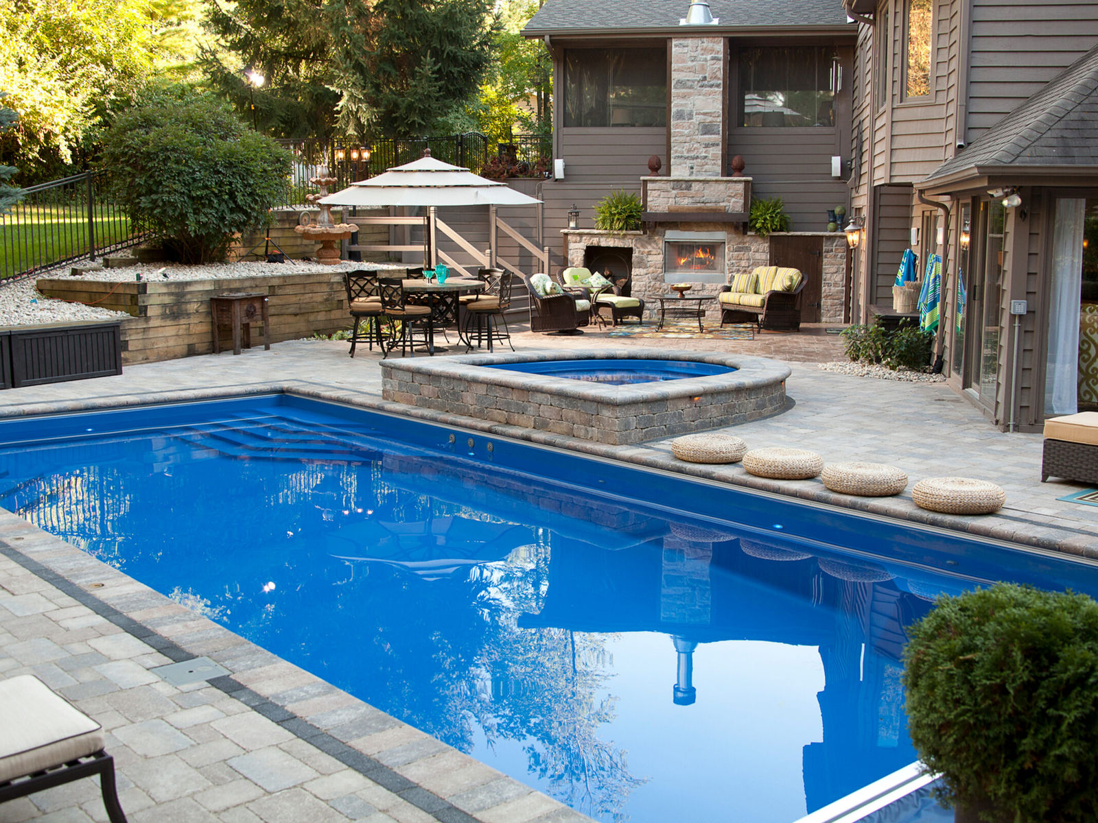 Fiberglass pool and spa with a stone fireplace and covered outdoor living space built by Dream Maker Pools